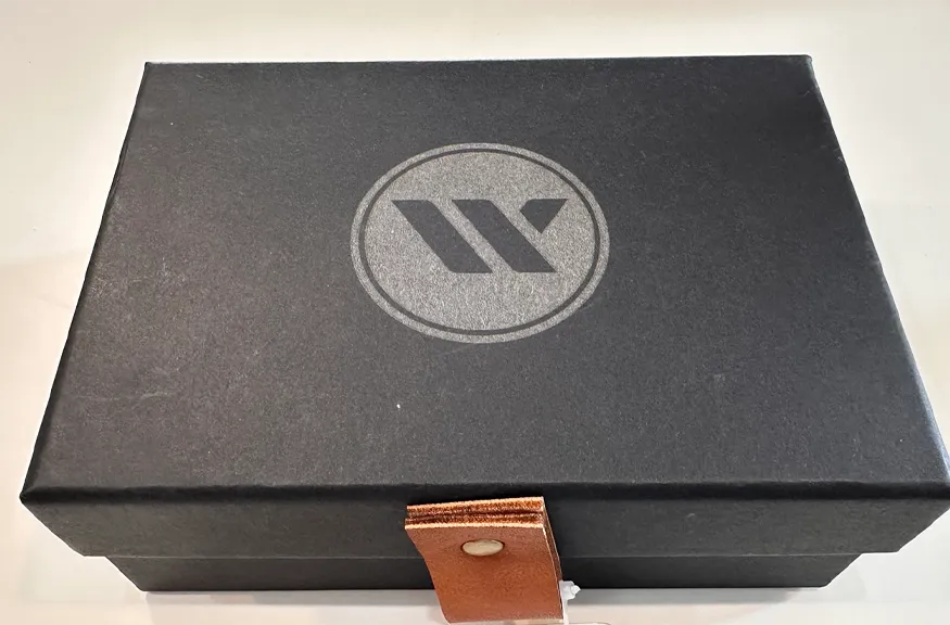 Top view of a matte black gift box featuring a silver Western Bid logo and a leather closure strap