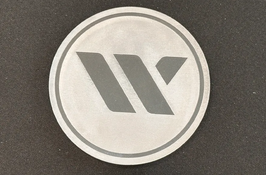 A circular metallic plate with a dark Western Bid logo engraved in the center
