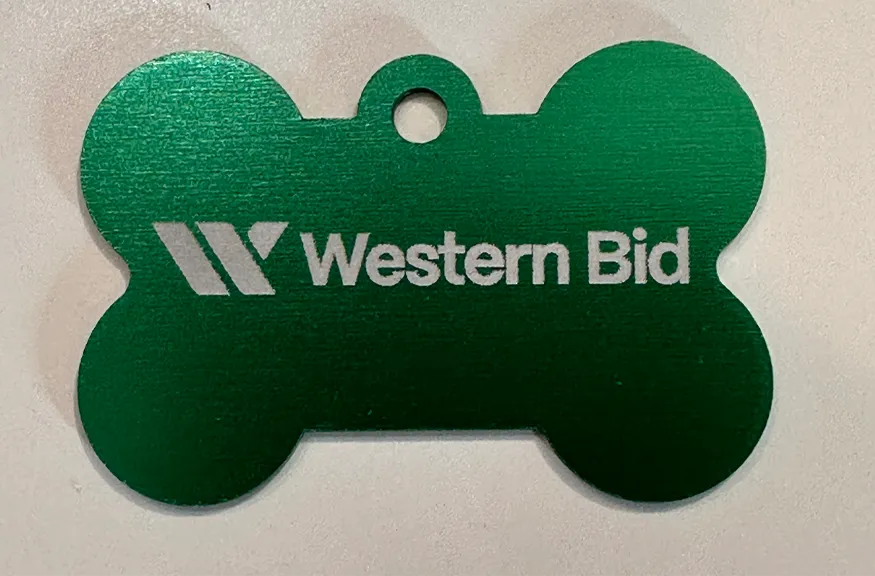 A green metallic pet ID tag shaped like a bone, featuring the Western Bid logo and text engraved in silver